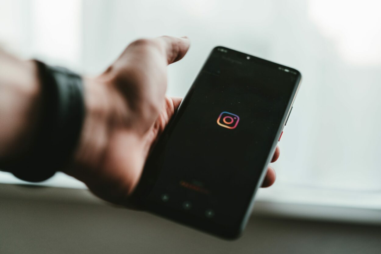 A man holding a phone with Instagram logo displayed on it