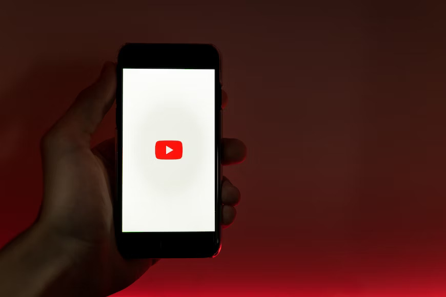 A hand holding a mobile with YouTube logo.