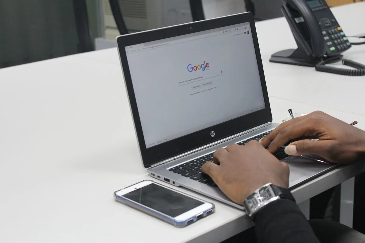 Person Typing on Google on a Gray and Black HP Laptop.