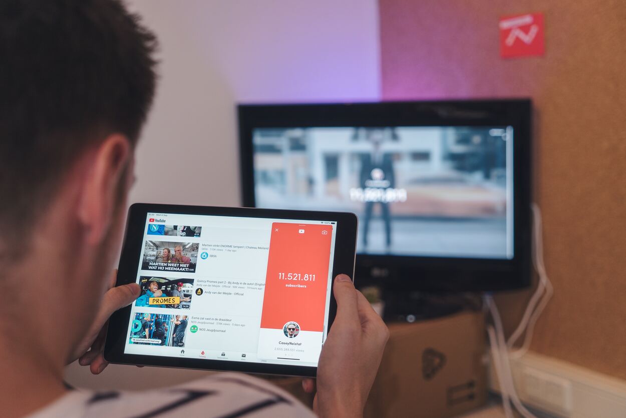 Man browsing YouTube sitting in front of TV.