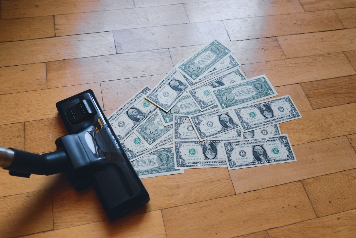 A pile of money getting sucked by a vacuum. 