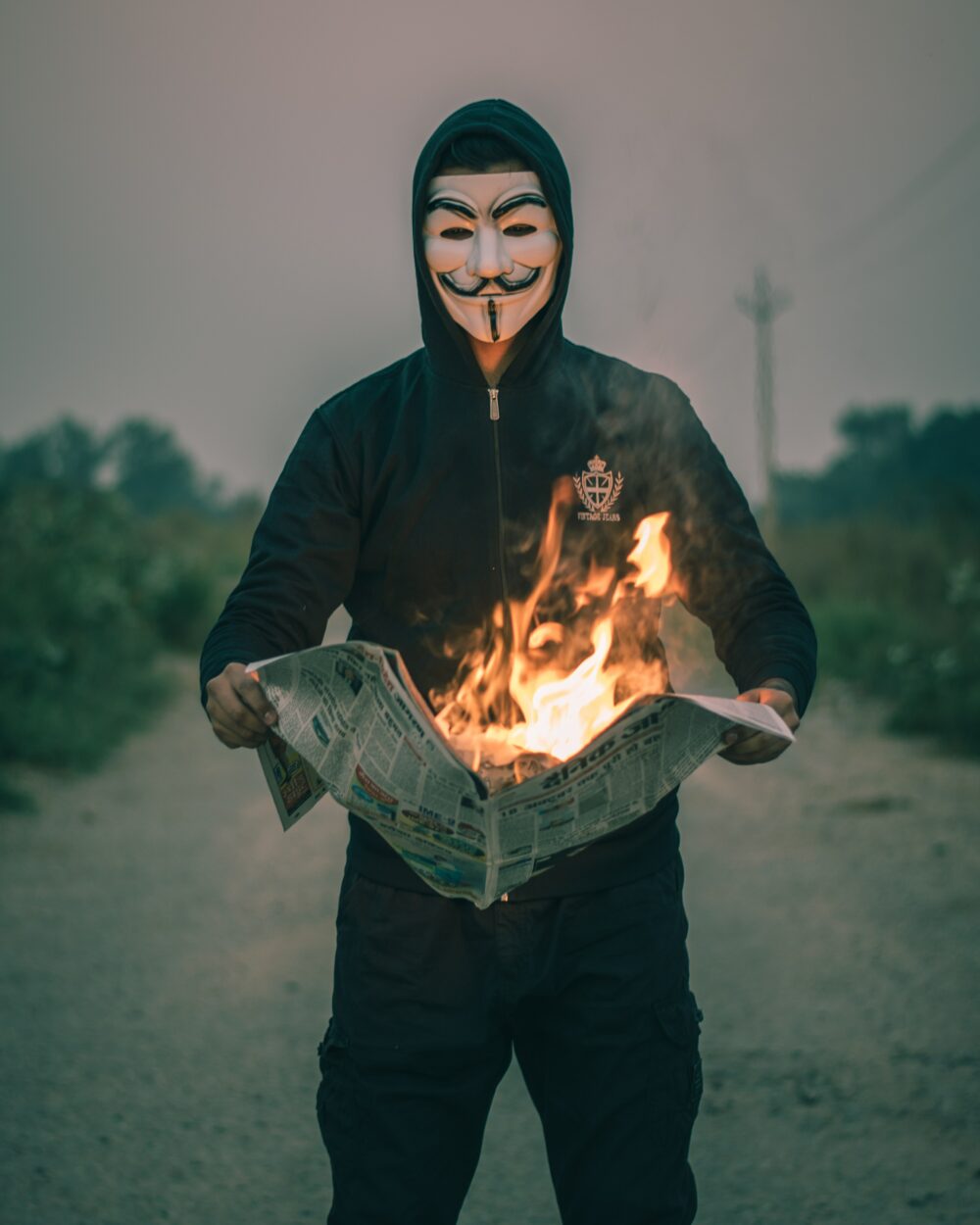 Person wearing an Anonymous Mask and burning newspaper