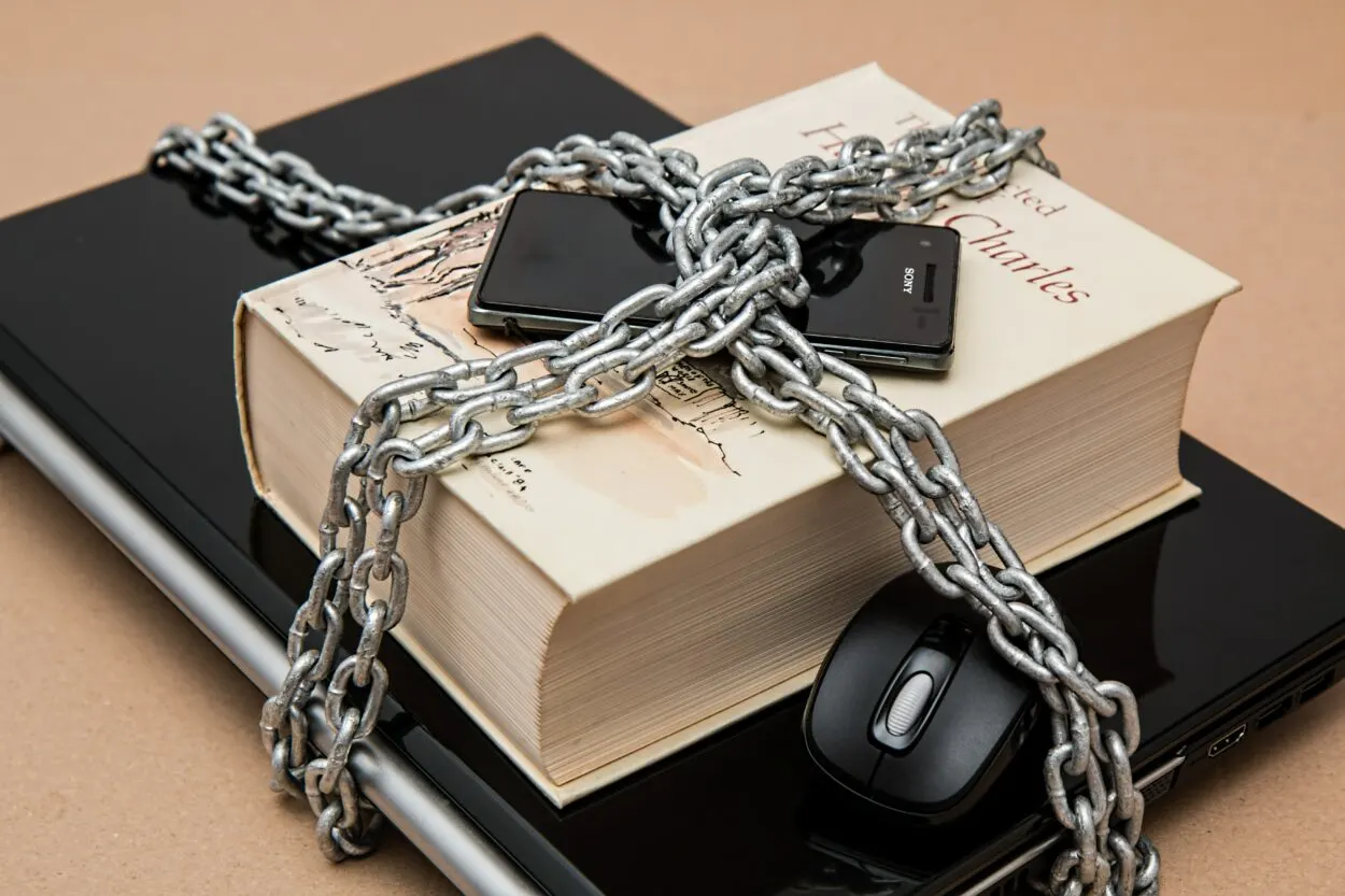 A Sony phone, a laptop, a mouse and a big book wrapped with a chain.
