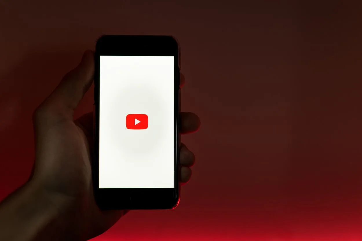 The YouTube logo on a phone in someone's hand