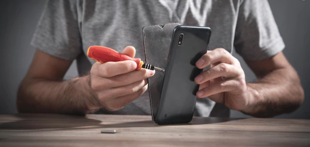 A man using a screwdriver to remove the old screen protector