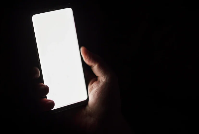 A hand holding a bright phone in the dark