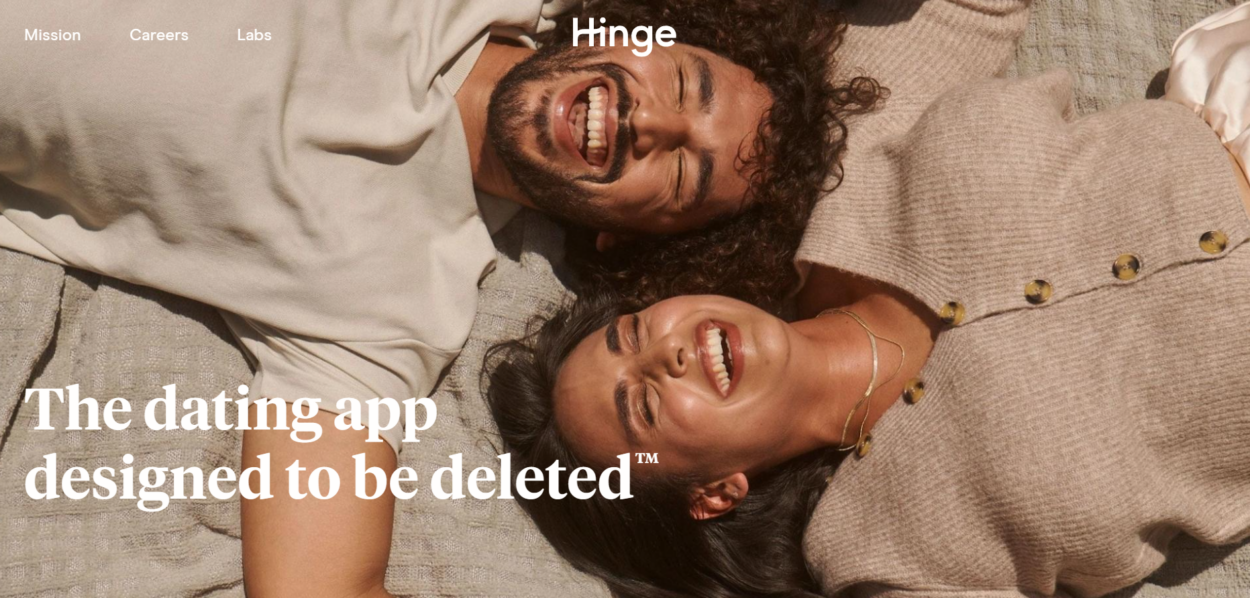 Hinge on browser. The image on the initial page showcases a man and a woman lying down and laughing.