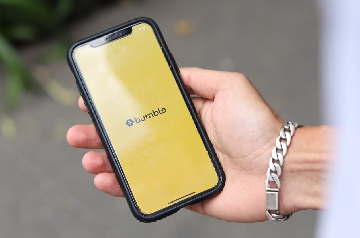 A hand holding phone, ready to use Bumble