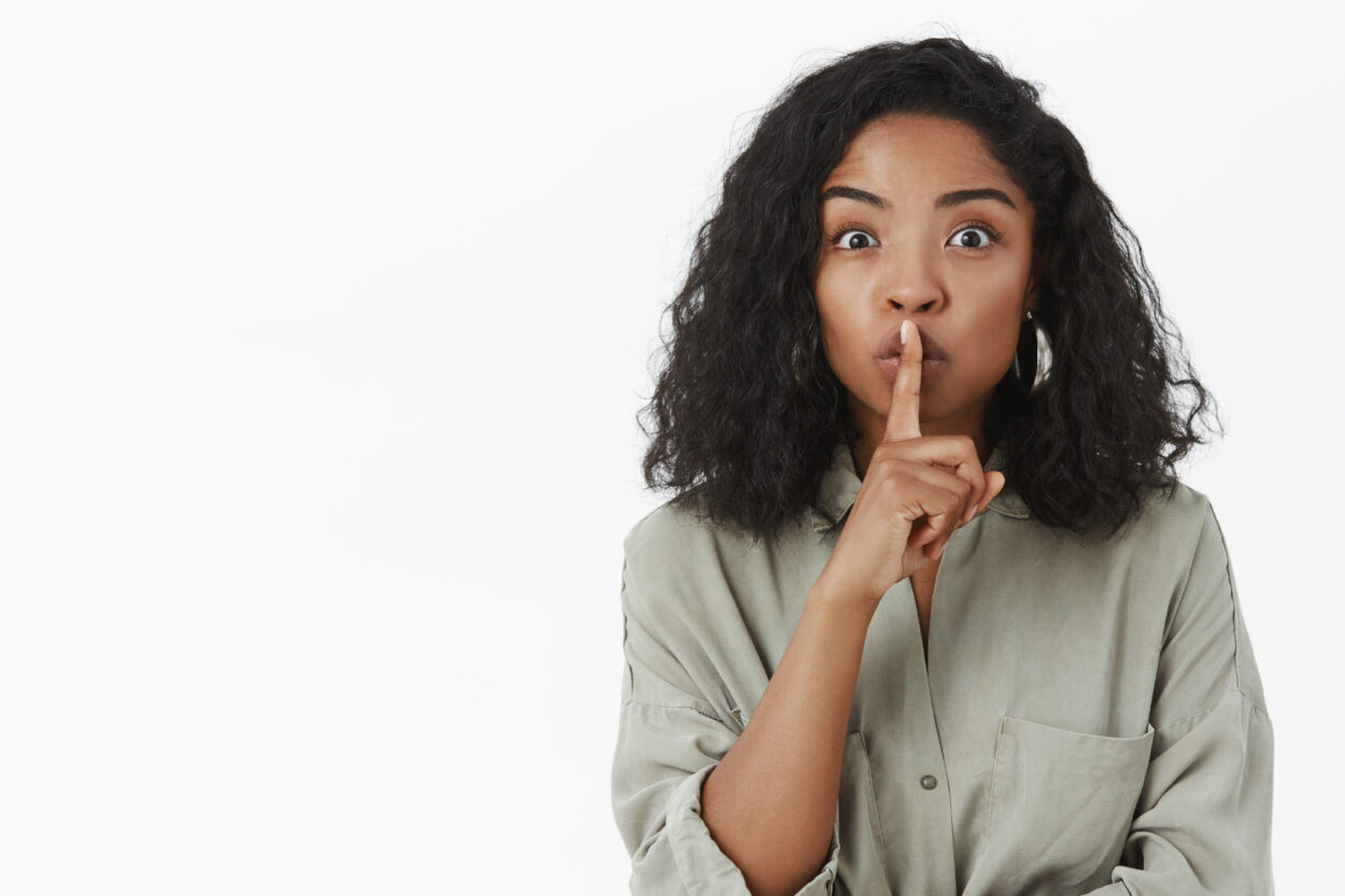 A girl pointing finger on her mouth indicating to keep a secret