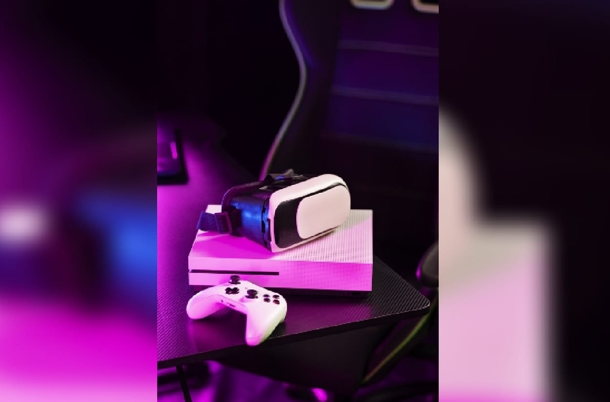 A white gaming setup on a desk with pink lights in the room